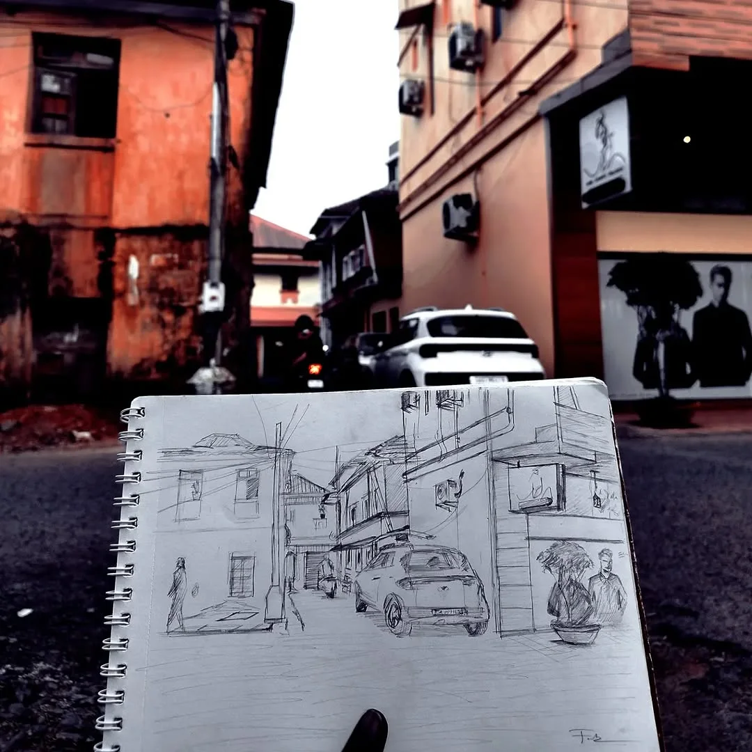 Urban sketchbook drawing of a street held up in front of the real scene it records
