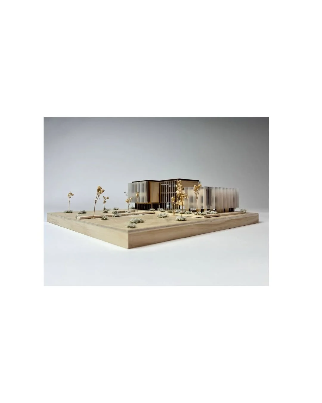 Warm lit wooden model of a small building with tiny figures on a clean backdrop